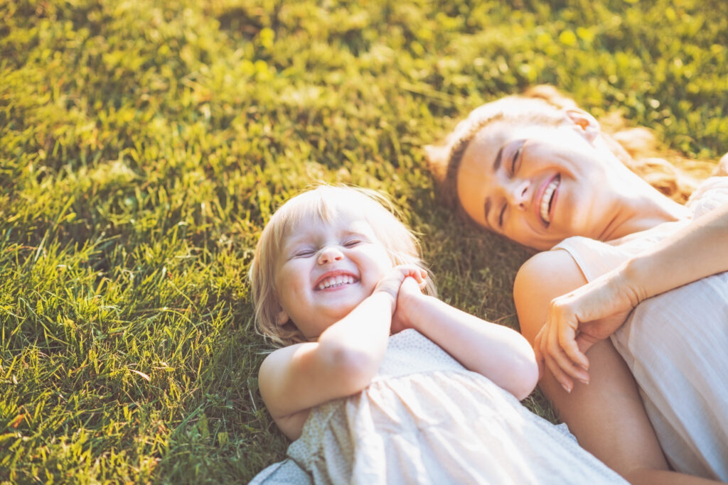 smiling,mother,and,baby,laying,on,meadow